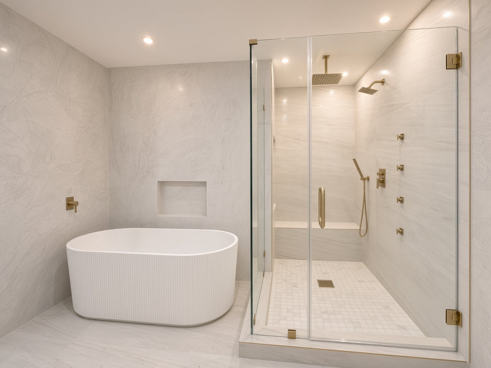 Bath with a freestanding fluted tub and a glass-enclosed shower with brass fixtures